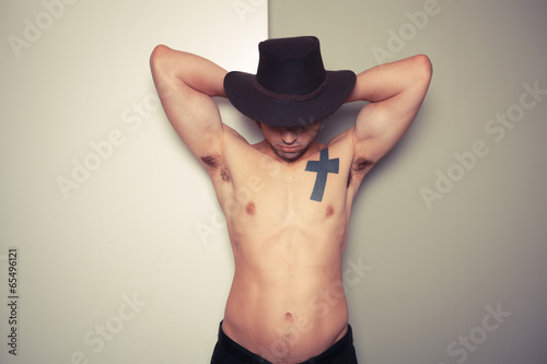 Shirtless young cowboy against dual colored background