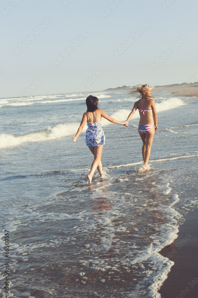 two attractive lesbian girls walking on the beach holding hands