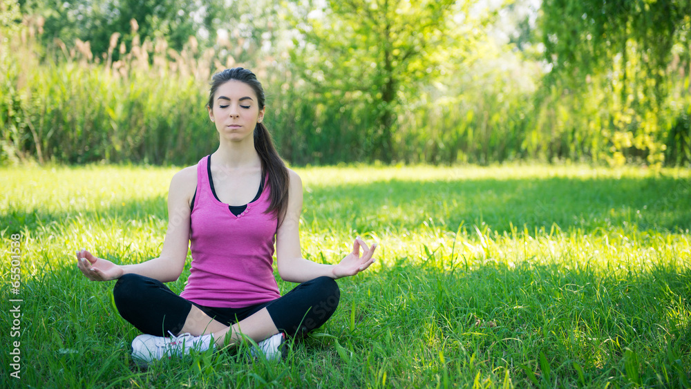 Young woman portrait practicing yoga outdoors in a park.