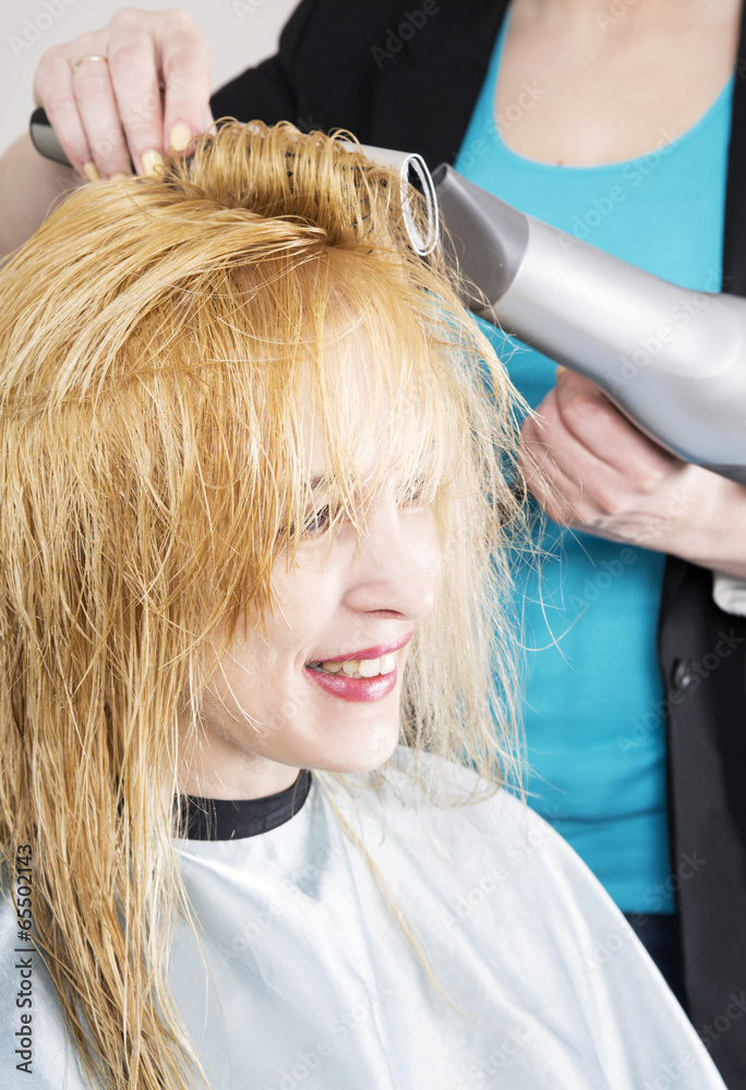 Fototapeta premium Hairdresser dries the hair dryer blond long hair