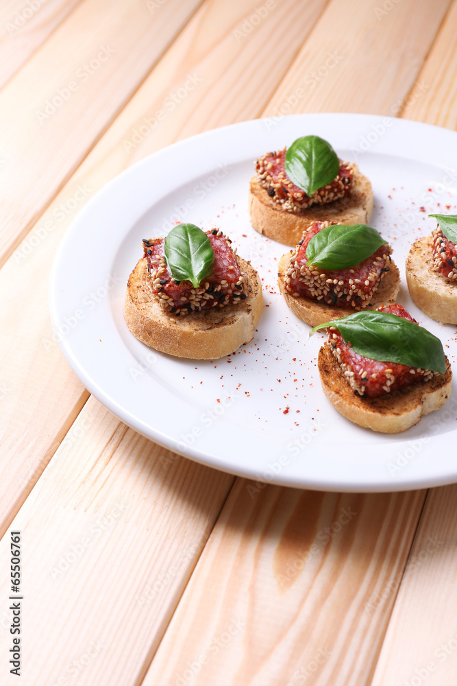 Tasty canapes with salami  and basil leaves,