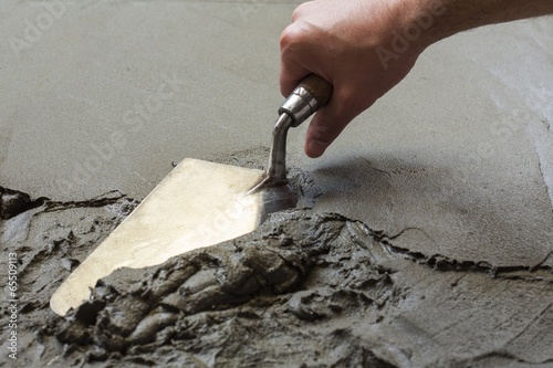 hand using trowel  with wet concrete floor