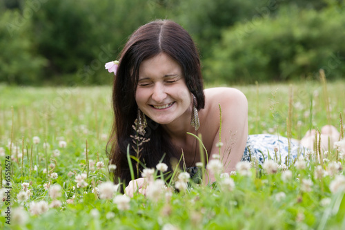 Beautiful happy Girl lying on grass field in summer park