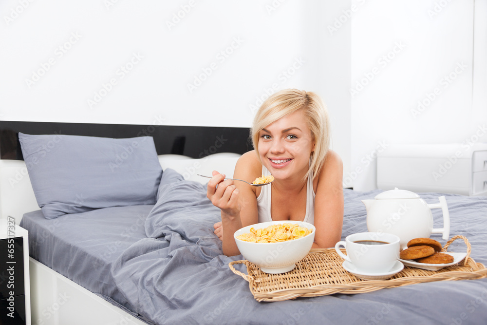 Breakfast in bed, young woman lying on bed