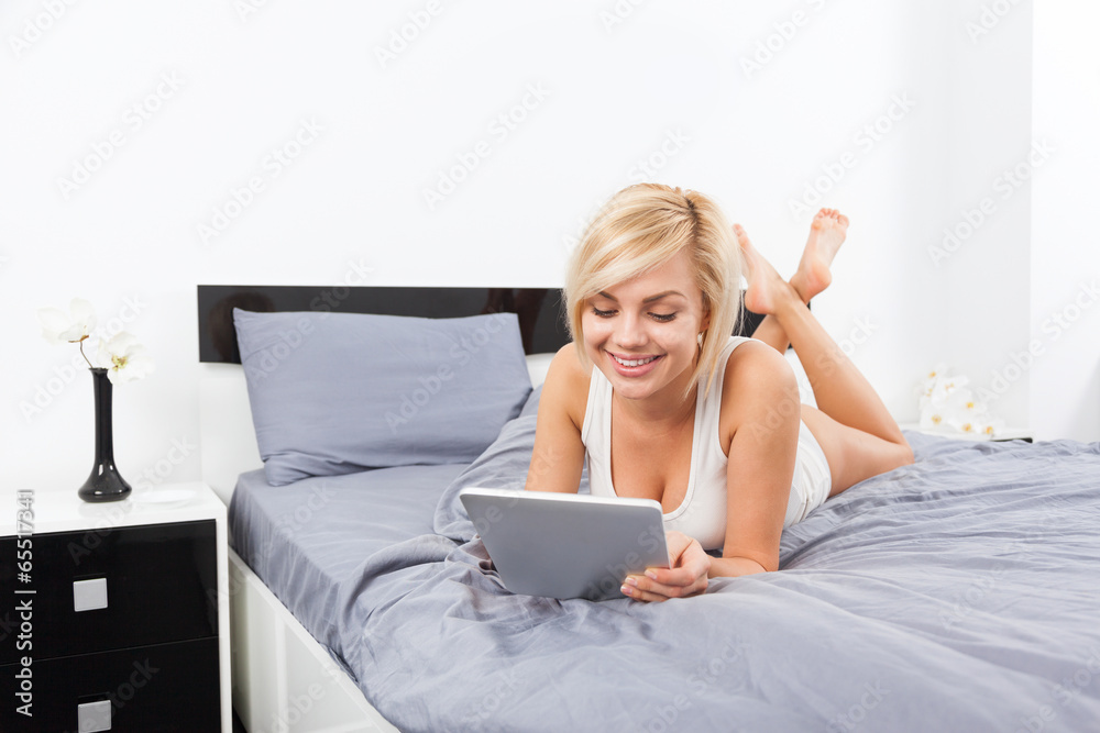 beautiful woman lying on bed using digital tablet beautiful woman lying on bed using digital tablet