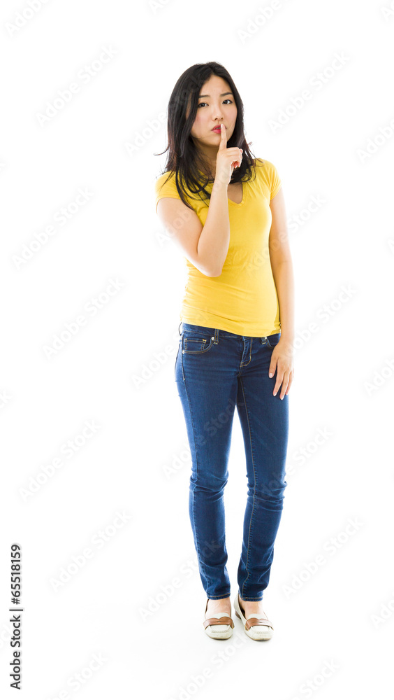 Young Asian woman standing with finger on lips Young Asian woman standing with finger on lips