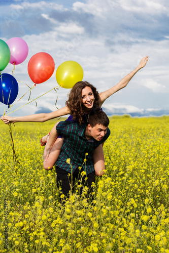 Happy couple with balloons on the yellow field