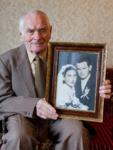 80 plus year old senior man holding his wedding photograph. photo