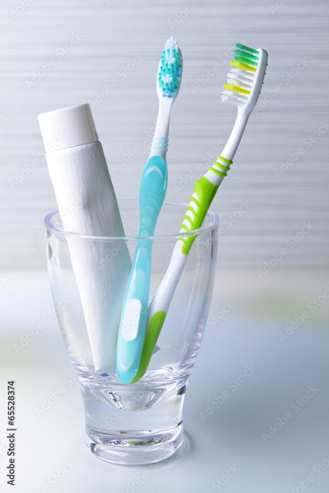 Toothbrushes in glass on table on light background Toothbrushes in glass on table on light background