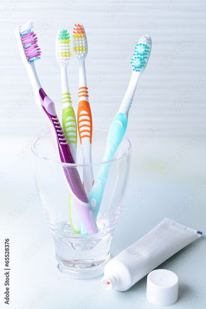 Toothbrushes in glass on table on light background Toothbrushes in glass on table on light background