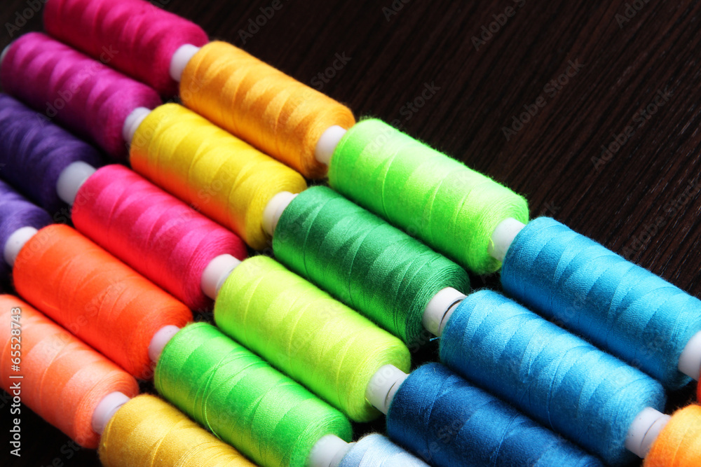 Multicolor sewing threads on wooden background Multicolor sewing threads on wooden background