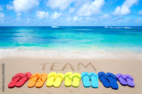 Sign "Team" and color flip flops on sandy beach