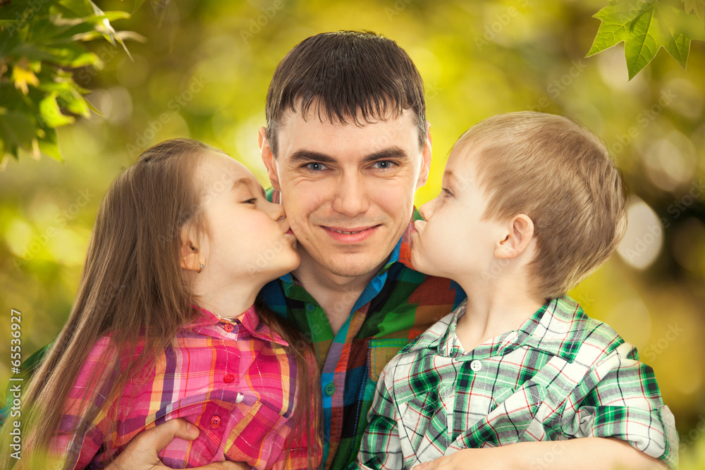 Fototapeta premium Happy doughter and son kissing their father