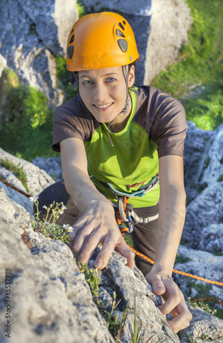 Smiling woman, rock climber in yellow helmet during sunset.