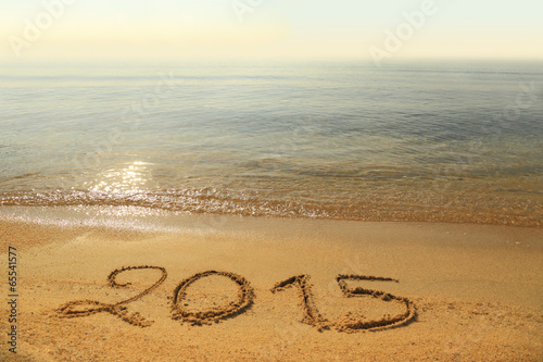 Year 2015 number written on sandy beach