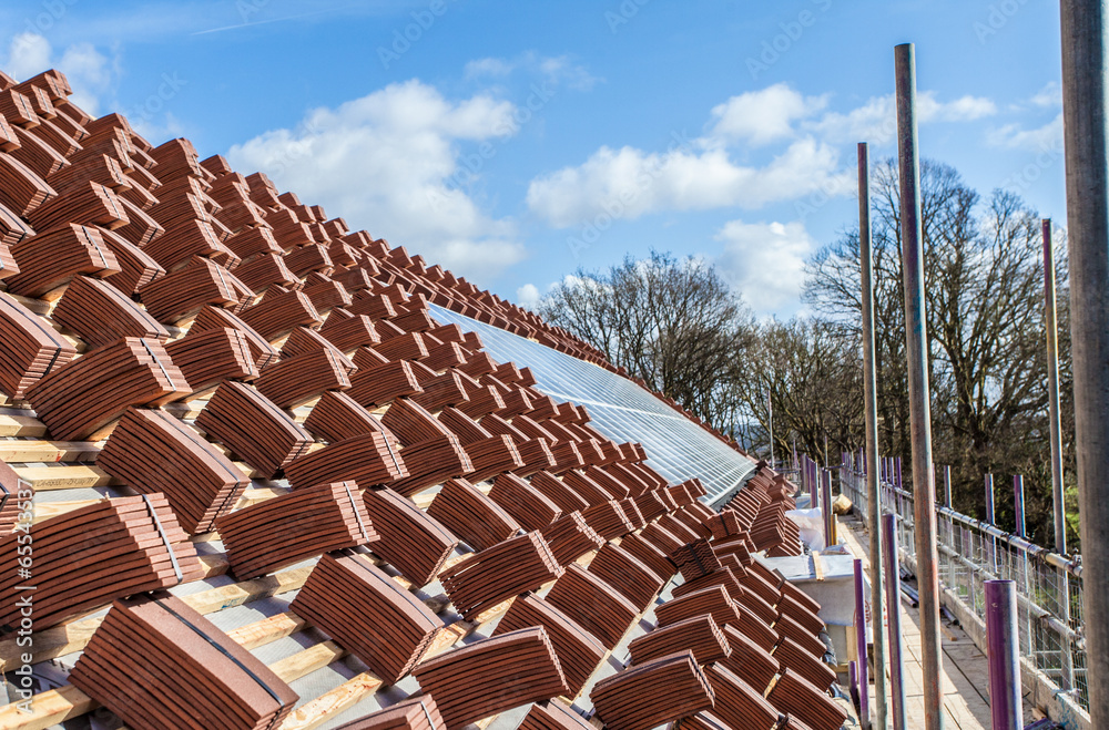 A roof under construction with stacks of roof tiles ready to fas