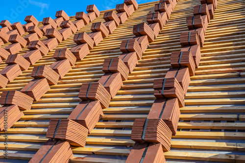 A roof under construction with stacks of roof tiles ready to fas