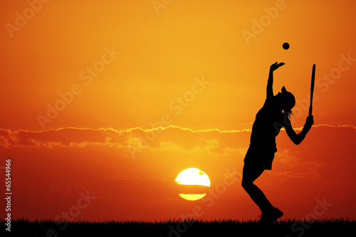 girl playing tennis at sunset