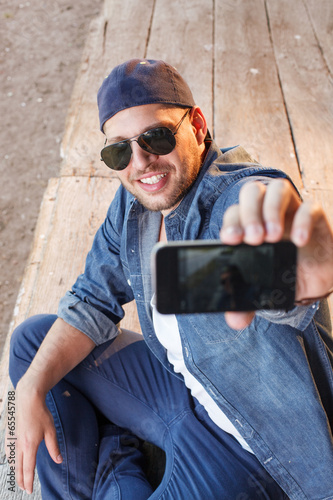 Handsome young man photographing seflie with smart phone photo