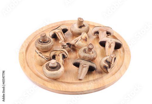 Sliced mushrooms on wooden platter.