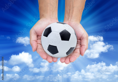 Soccer ball on hands isolated on blue sky  background © littlestocker