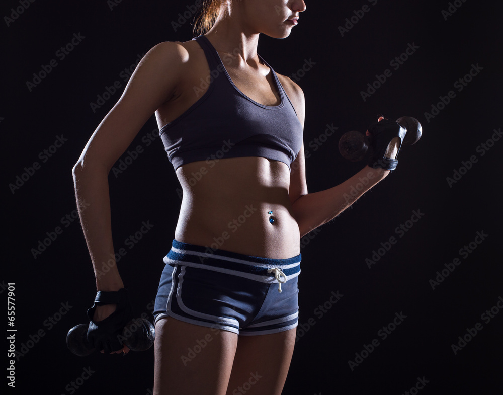 Torso of a young fit woman lifting dumbbells Torso of a young fit woman lifting dumbbells