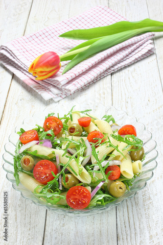 Salad with pasta, arugula, tomato, onion and green olives
