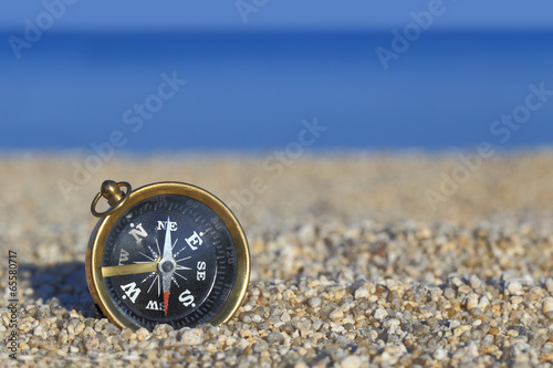 Old compass on the beach with sand and sea