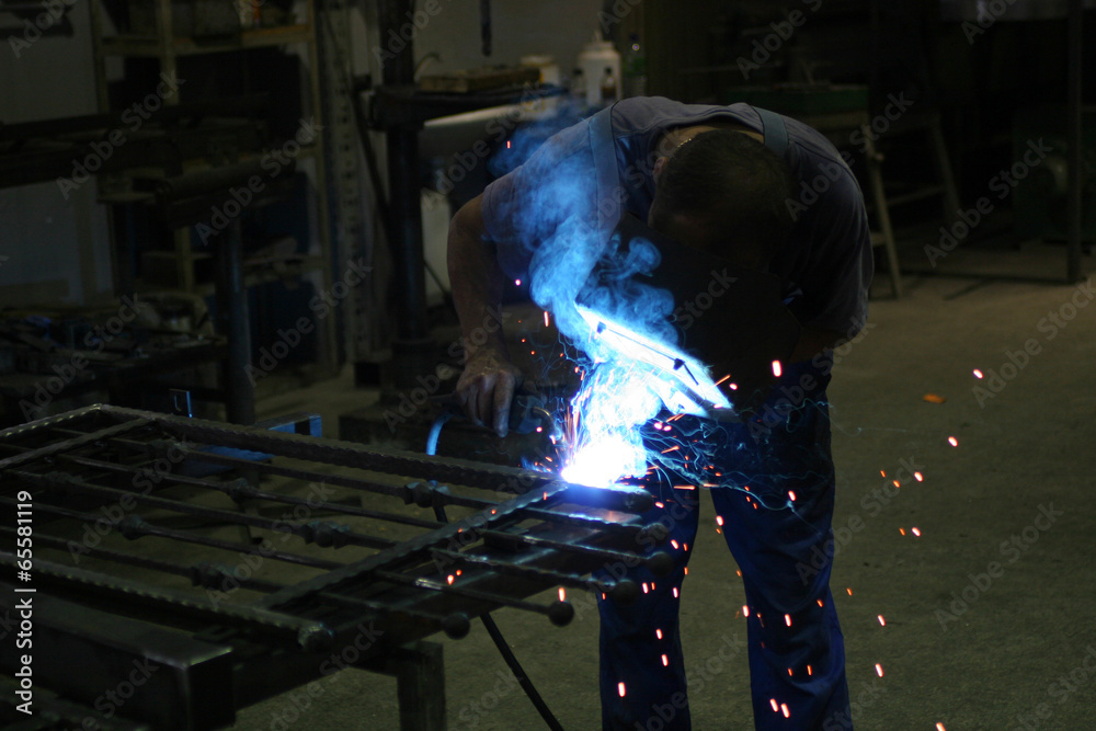Welder in a workshop making a fence Welder in a workshop making a fence
