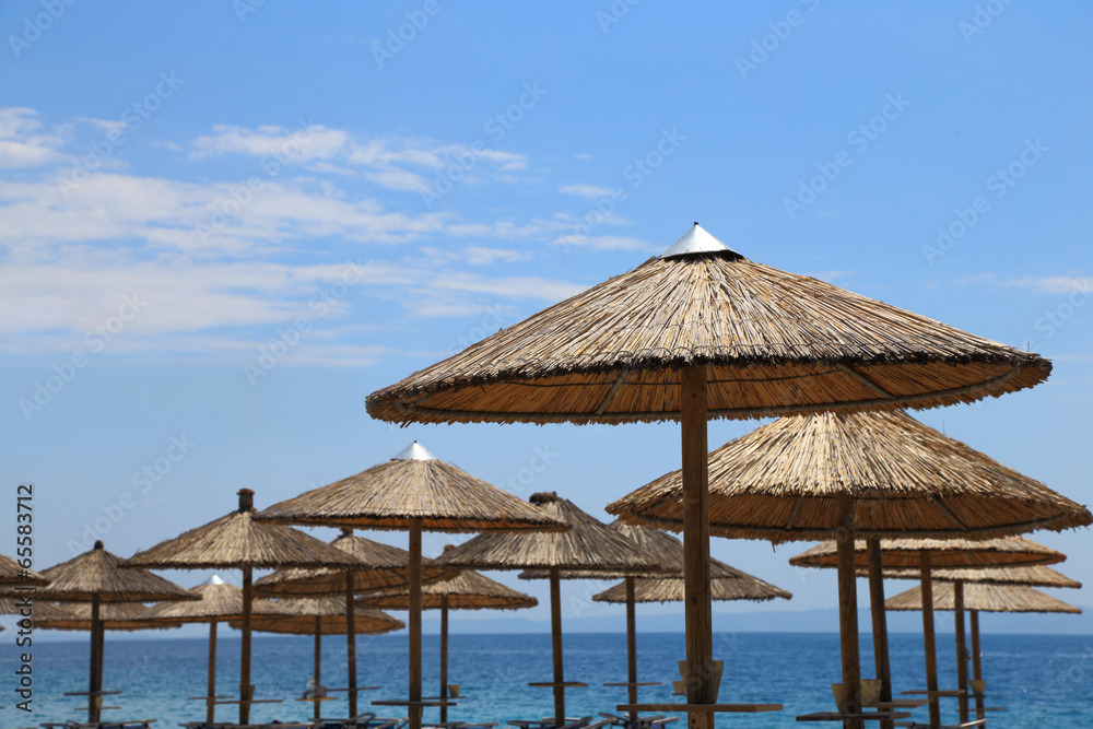 Sunny beach with wicker umbrellas and blue sky