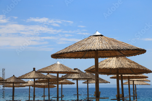 Fototapeta Naklejka Na Ścianę i Meble -  Sunny beach with wicker umbrellas and blue sky