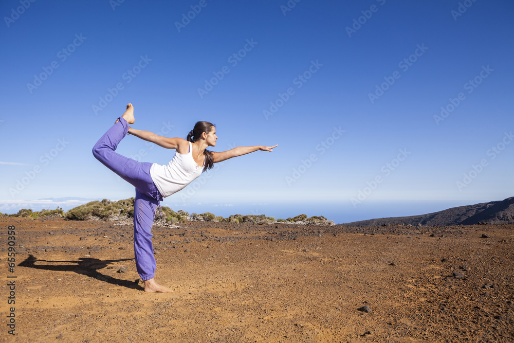 Young attractive woman doing dancers yoga pose outdoors on a des Young attractive woman doing dancers yoga pose outdoors on a des