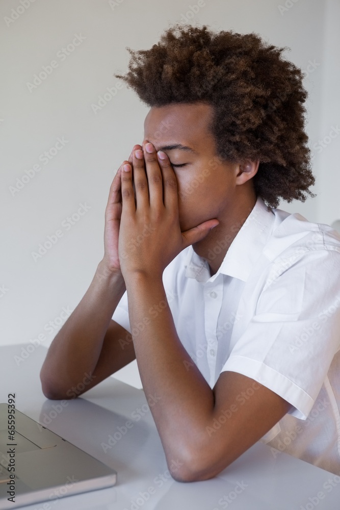 Casual businessman feeling exhausted at his desk