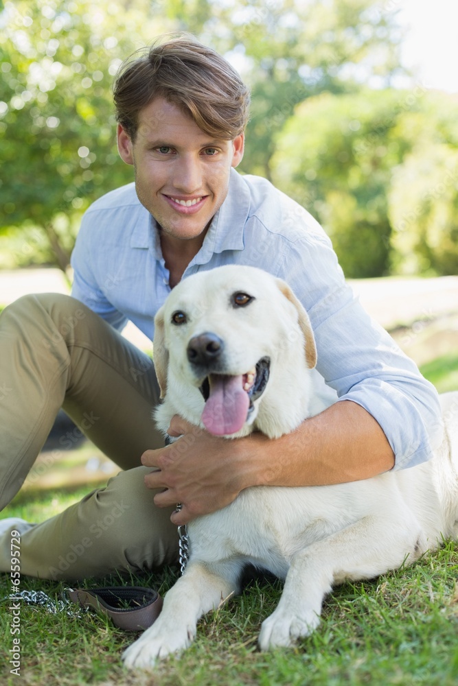 Handsome smiling man with his labrador sitting in the park Handsome smiling man with his labrador sitting in the park