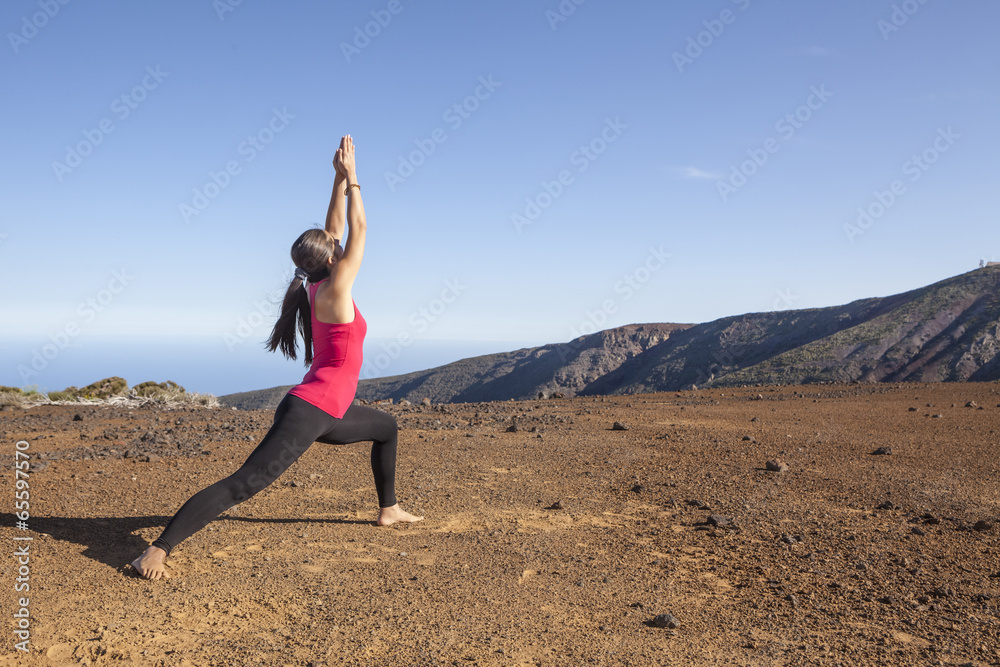 Young woman practicing yoga warrior pose on a desert mountain Young woman practicing yoga warrior pose on a desert mountain