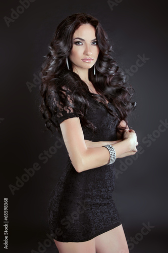 Brunette woman with long curly hair posing in dress, isolated on