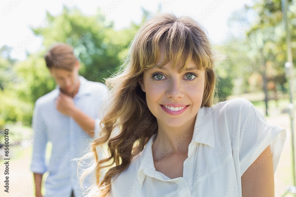 Beautiful blonde smiling at camera with boyfriend in background