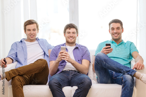 smiling friends with smartphones at home