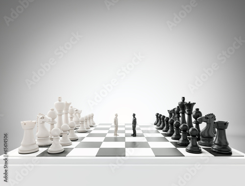 Two tiny figures standing on a chess board photo