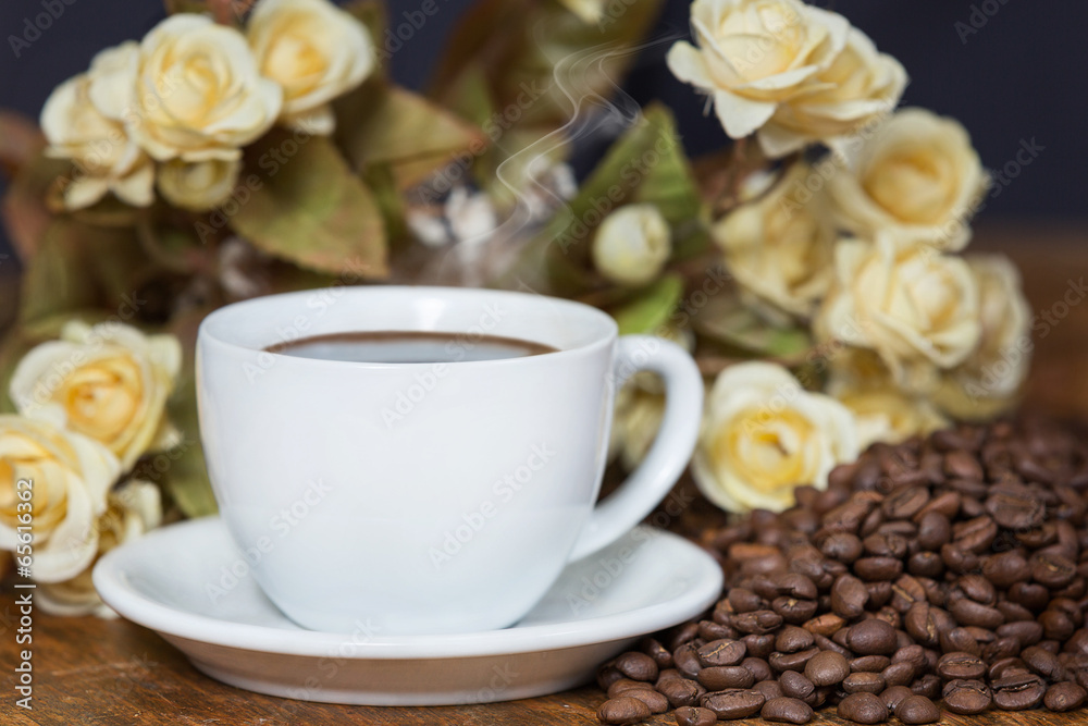 Obraz premium Beautifully arranged cup of coffee among beans and flowers.
