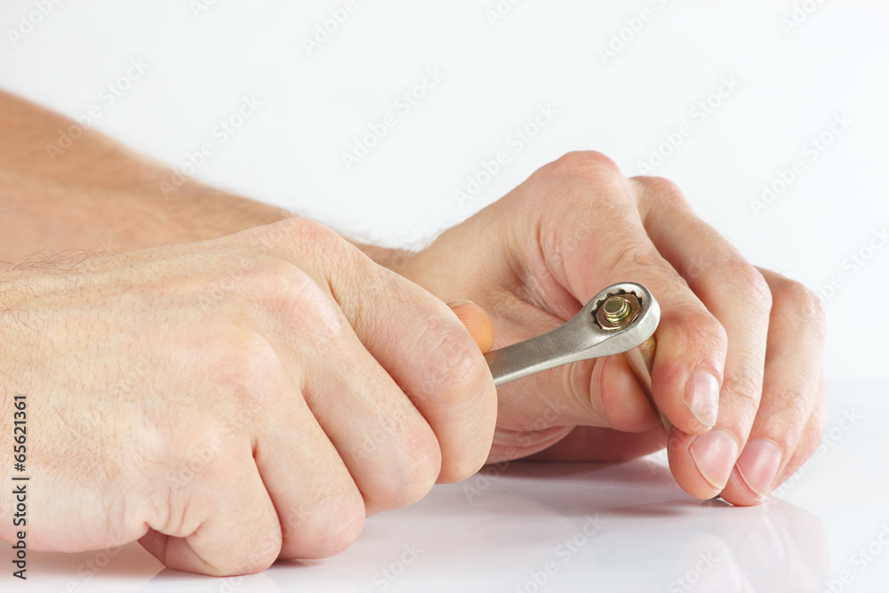 Hand of repairman with a wrench to tighten the nut Hand of repairman with a wrench to tighten the nut