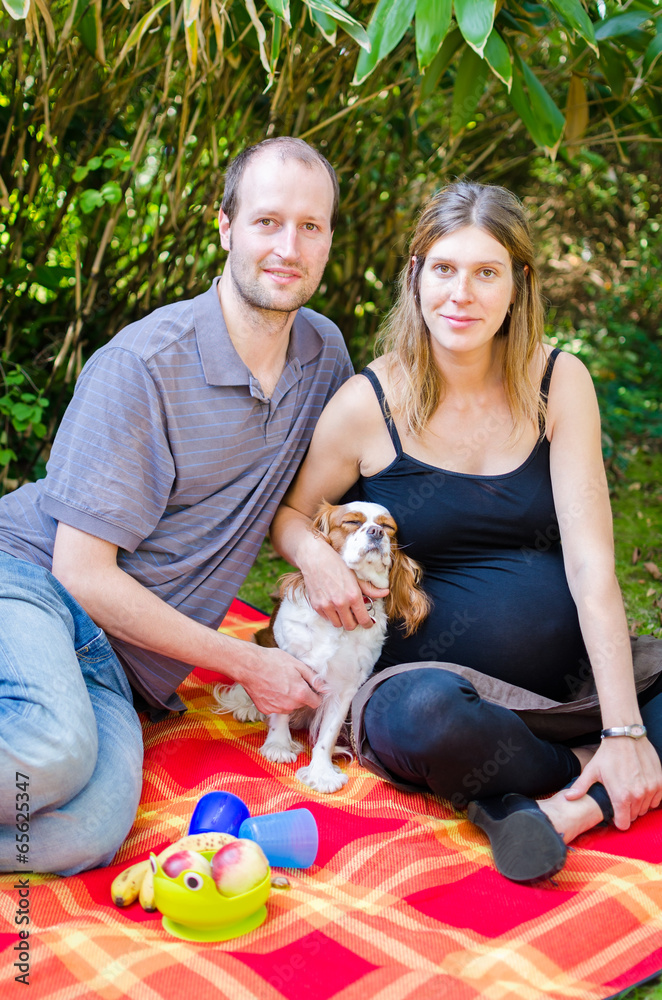 Happy family with their dog and pregnant motherin park