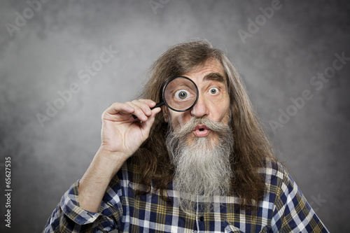 Senior old man looking through zoom magnifying glass, amazement
