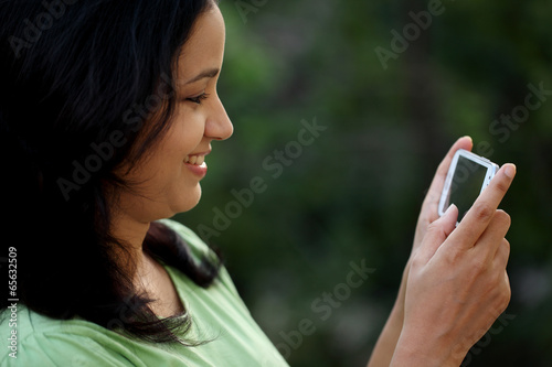 Happy young woman text messaging at outdoors photo