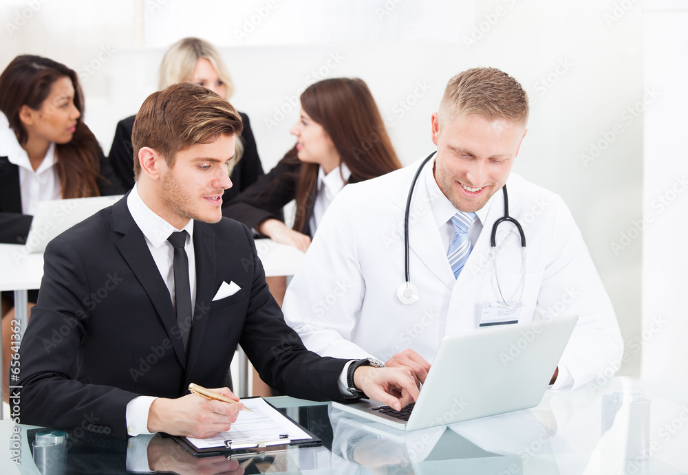 Doctor And Businessman Discussing Over Laptop