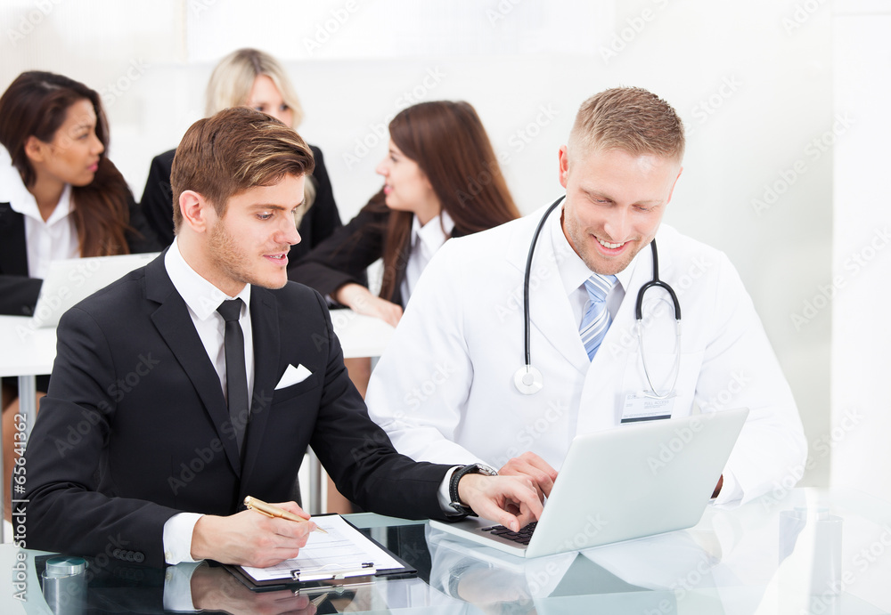 Doctor And Businessman Discussing Over Laptop Doctor And Businessman Discussing Over Laptop
