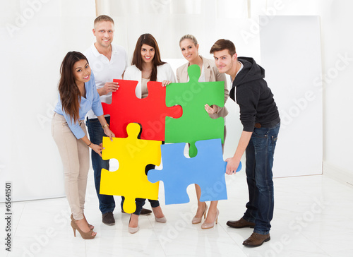 Confident Businesspeople Joining Puzzle Pieces