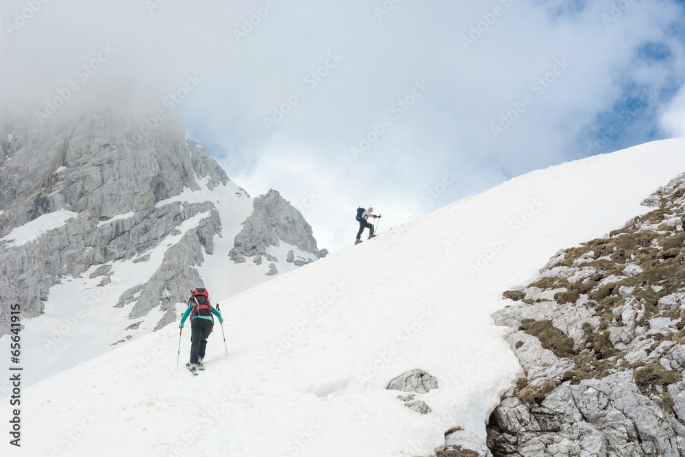 Skiiers ascending mountain slope