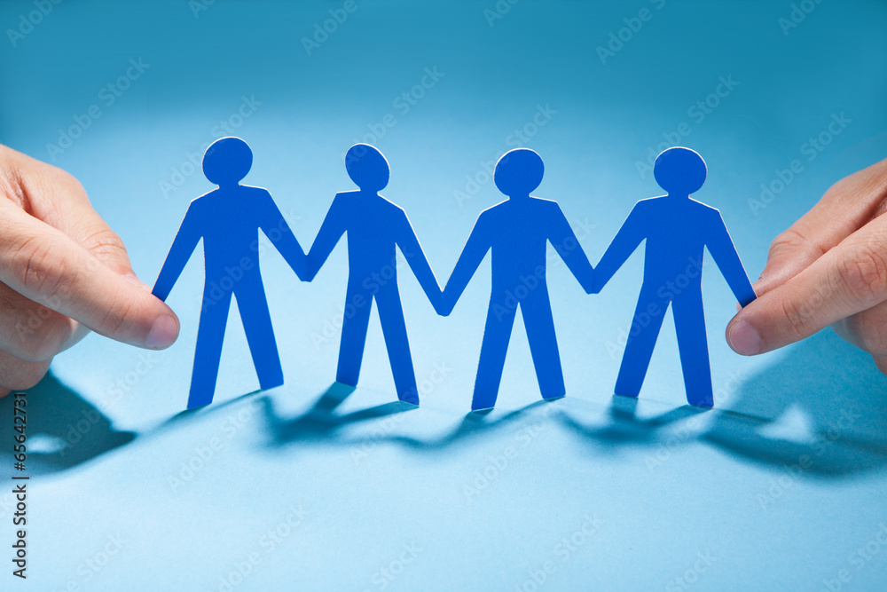 Businessman's Hands Holding Paper People Chain On Desk Businessman's Hands Holding Paper People Chain On Desk