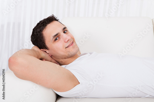 Smiling Man Relaxing On Sofa At Home